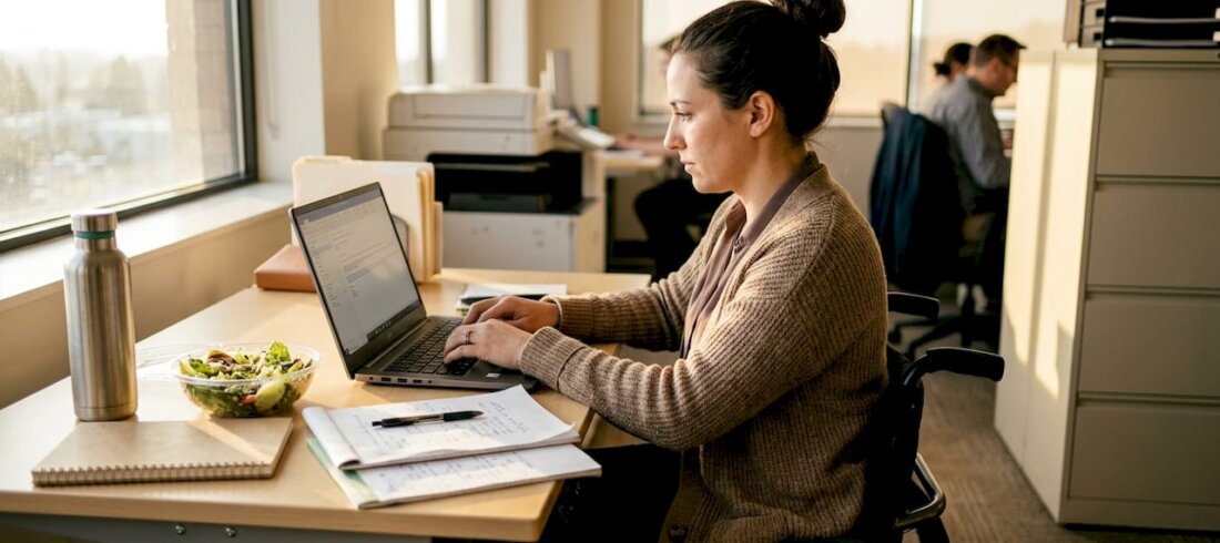 Wheelchair user working at cluttered office desk Wheelchair user working at cluttered office desk